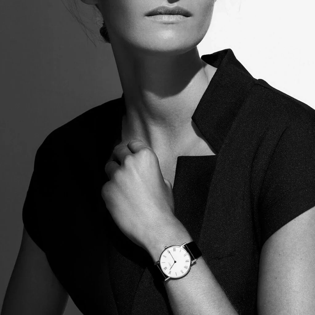 A sleek Ole Mathiesen watch with a minimalist design, featuring a clean white dial, black leather strap, and silver casing, showcased against a dark background.